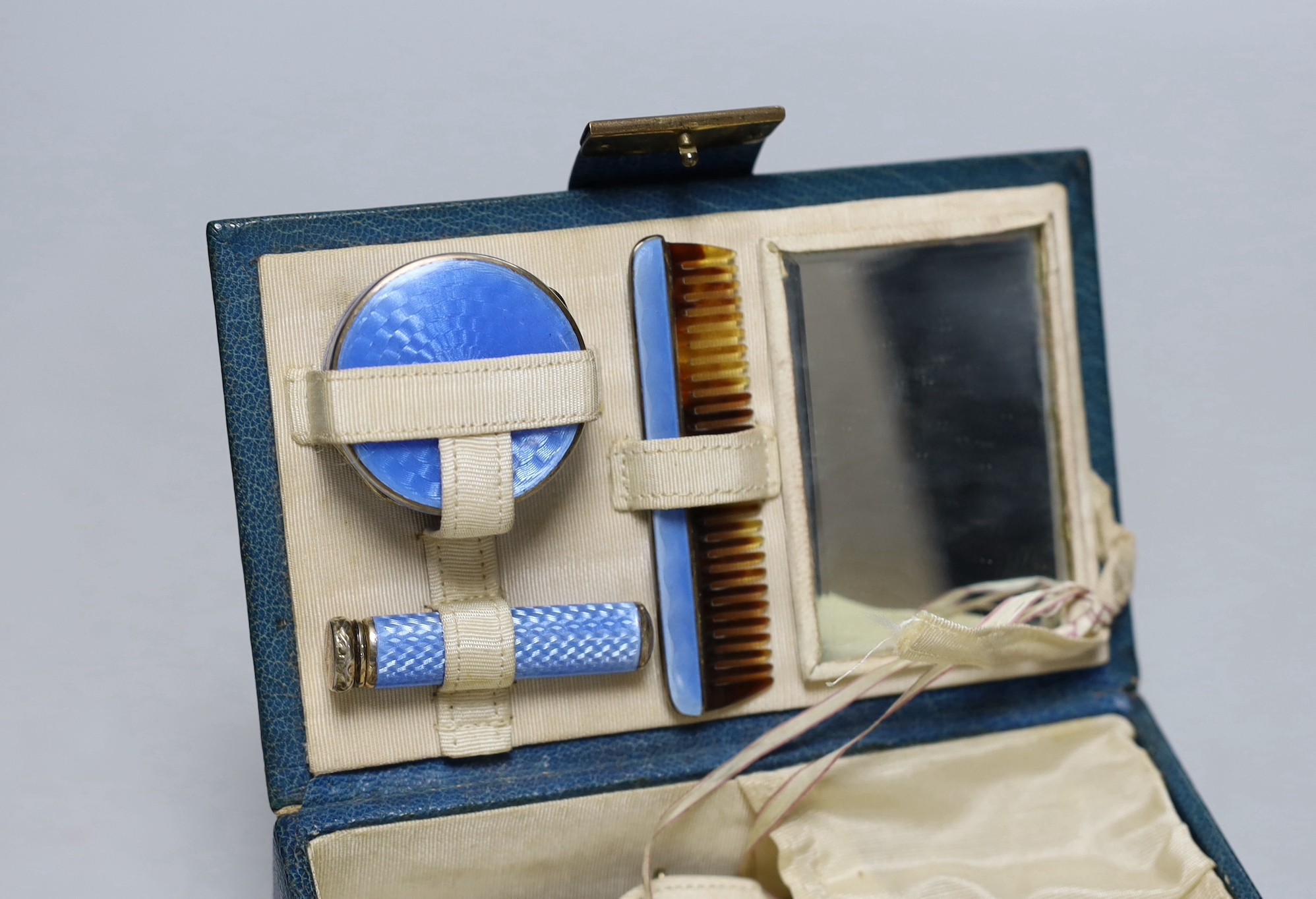 A lady's 1920's small leather vanity case, containing an enamelled comb, pill box and lipstick holder, the latter two with silver hallmarks, one for Cohen & Charles, London, 1926, the other with import marks only, case 1